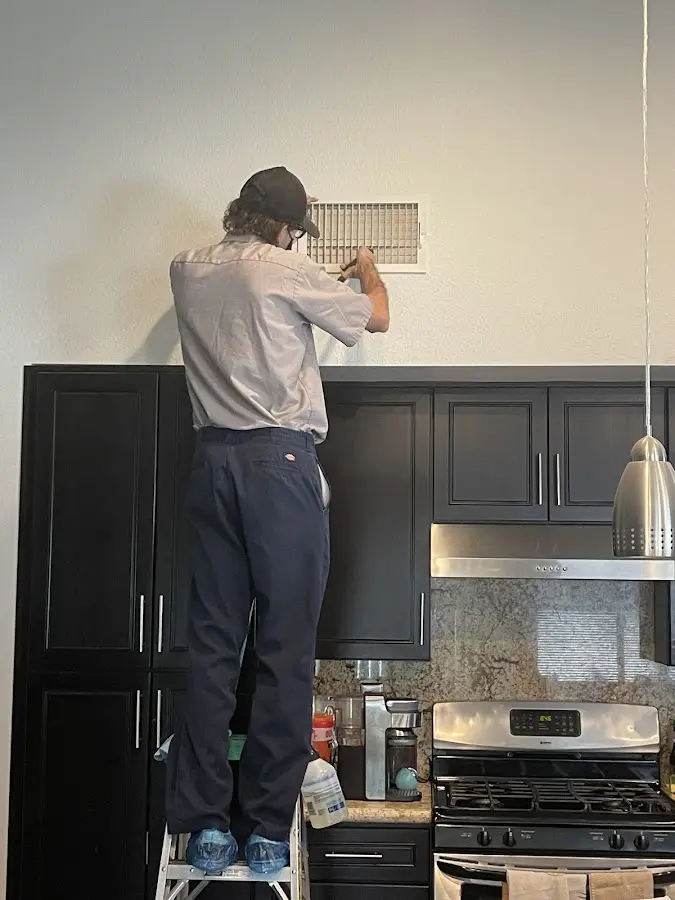 Technician inspecting an air vent during HVAC service in Sequim